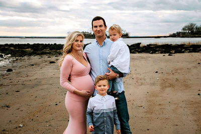 Connecticut maternity photographer documents family of four with pregnant mother on beach during golden hour