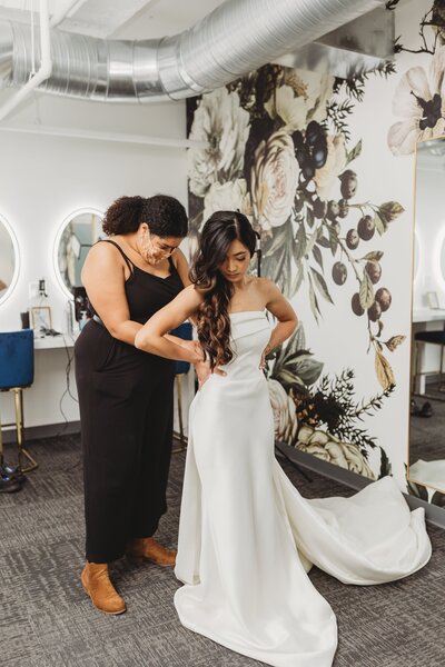 Wedding planner helps a bride into her dress at Outreach Event Space in downtown Kansas City