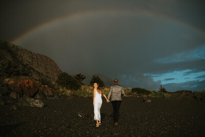 couple walking out on cliff over fall mountains as groom kisses the brides hand at arctic valley