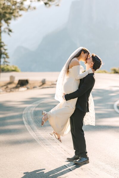 Wedding couples snuggles at sunrise during their elopement at Glacier Point in Yosemite.