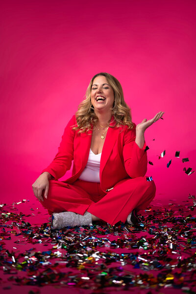 A woman smiling while sitting in confetti.