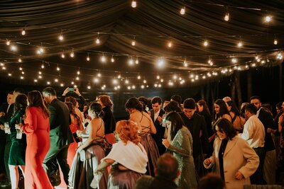 Wedding guests dance underneath ambient market lighting