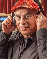 Billy Safier, an OPWF board member, smiles wearing headphones. 
