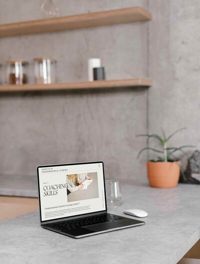 A laptop screen reads "Coaching Skills" while sitting on a kitchen counter.