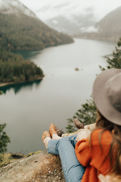 couple sitting on a mountain overlooking water