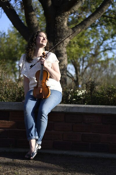 Violinist and Franklin Method Dr. Erika Burns looks up sitting in front of a tree.