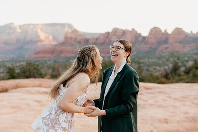 queer lesbian couple getting married on top of a mountain in Sedona Arizona and laughing
