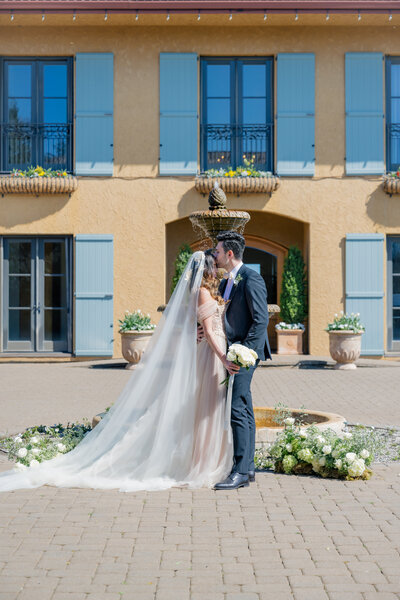 bride and groom pose in front of villa fountain wedding day