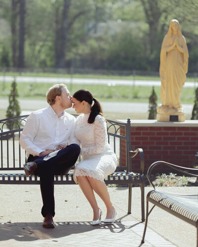 A couple poses in front of a Mary statue during their engagement session at St. Mary's Catholic Church in Jackson, Tennessee.