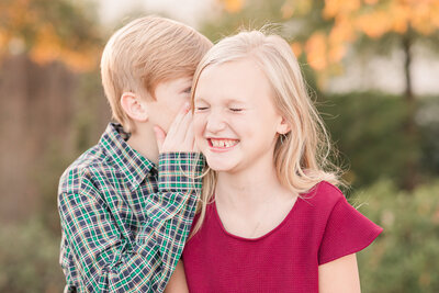 brother whispering in sister's ear