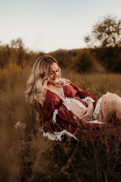 Photo of a woman embracing her belly during her maternity photoshoot in a field in Bloomington Indiana.