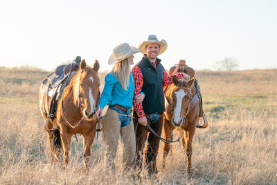 Wynnewood Oklahoma horse trainers Amanda and Nick of Topwind Ranch stand together between their two chestnut Quarter Horses. Amanda is looking up at Nick while embracing his arm.
