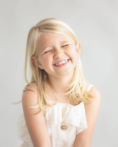 Gorgeous studio portrait of little blonde girl being silly
