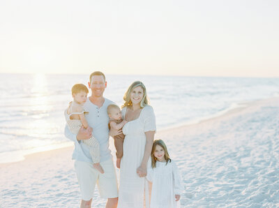 Mom, dad and three kids smiling at the camera on Santa Rosa Beach, FL