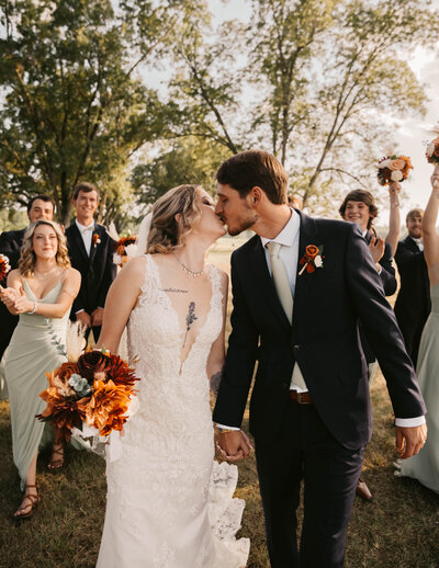 Bride and groom kissing as they walk down the aisle together at The Farm at Lullwater in Opelika, AL.