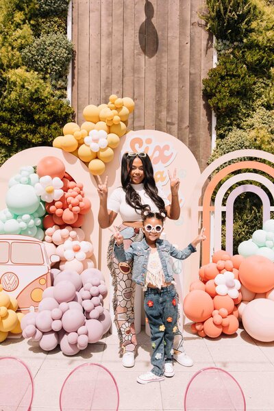 A girl and her mother pose in front of  the garden wall for her birthday party at Hart and Main