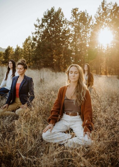 A group of women meditating in a field together