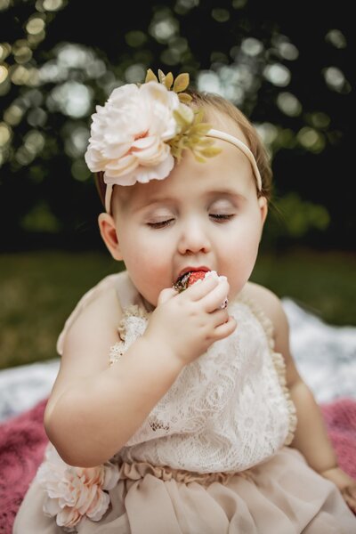 baby girl eats cake and strawberry at a photo session