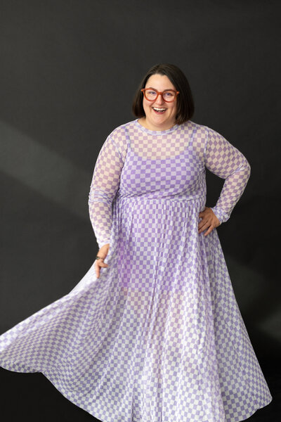 Founder of SDK Sydney in purple checkered dress in front of charcoal background