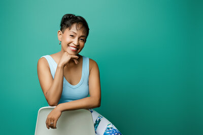Woman poses for headshot with teal background