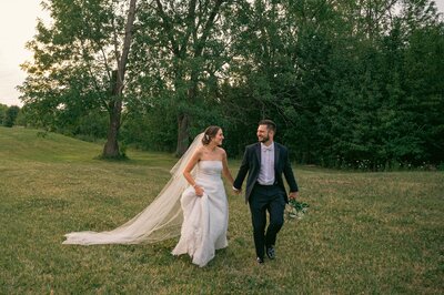 bride and groom holding hands while walking towards camera