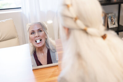 Adult patient practicing myofunctional therapy exercises in the mirror.