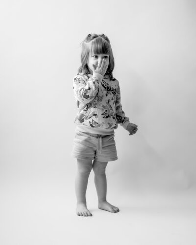 Toddler girl wearing Bluey shirt and shorts kissing her hand to blow a kiss.