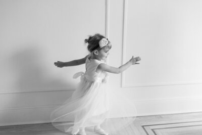 Une petite fille qui tourne avec sa belle robe blanche.