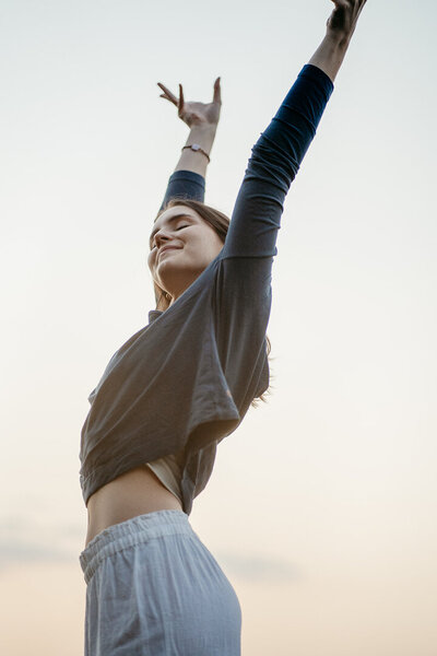 Tessa Adrian in einer Yoga-Pose auf einem Feld, Natur im Hintergrund.