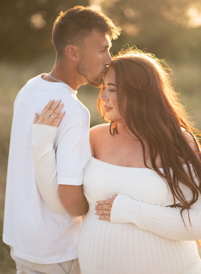 Couple together holding baby bump at sunset – outdoor maternity session in Poole, Dorset