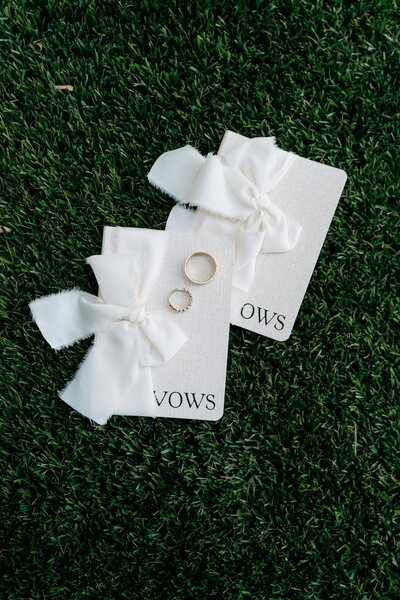 Close up of cream vow books wedding detail photo with gold wedding bands