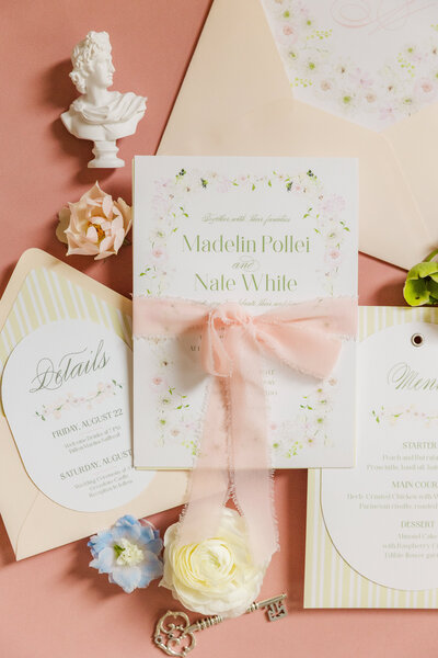 Flay lay set up of beautiful wedding invitations featuring pops of white, pinks and greens at the Greystone Castle in Boulder, Colorado.