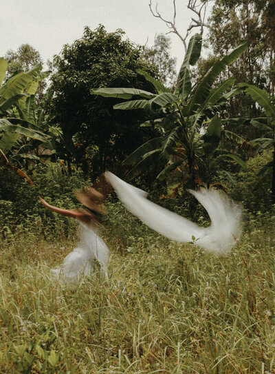 Lady running through the bush, carrying a piece of material behind her