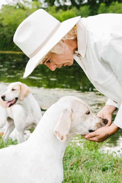 Sasha petting white lab dogs on farm