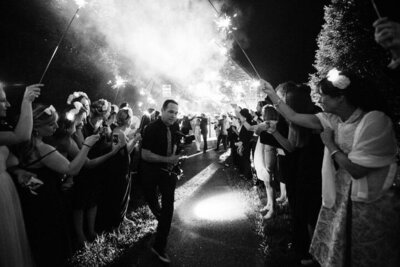 A group of glittering people with sparklers walking down a path captured by a talented Texas wedding videographer.