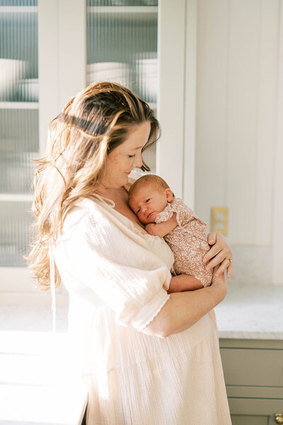Mom cradles baby for newborn photos in her light-filled kitchen in Central PA.