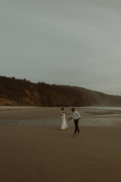 Couple's shoot at sunset on the Oregon Coast. The couple is walking across from each other in a circle with their arms outstretched to each other.