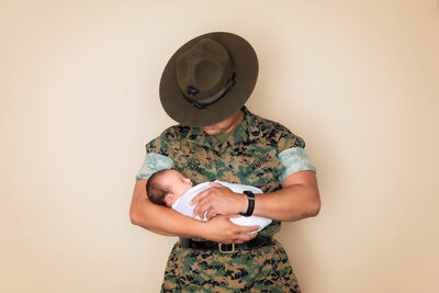 Newborn photographer, a marine father in uniform holds his newborn son