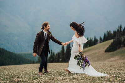 bride and groom holding hands on a mountain top