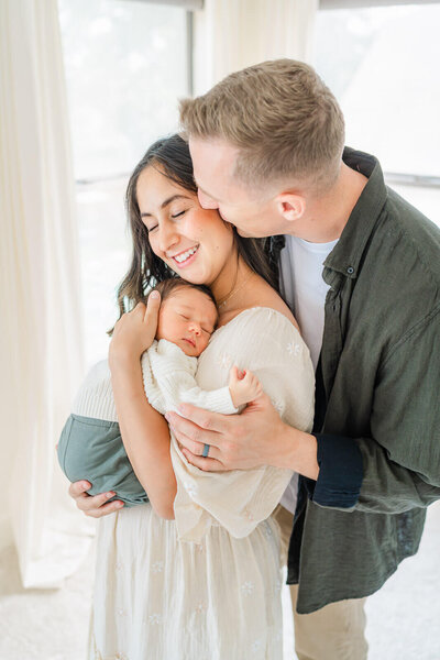 A couple snuggles while holding their infant during their Austin newborn photography session.