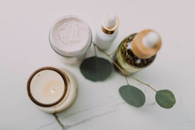 Flatlay of skincare items, candle, and essential oils styled on a marble surface, representing the photographer’s favorite self-care routine.