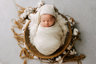 Newborn baby girl on a pink background with a pink flower headband