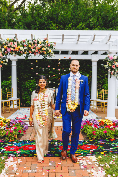 Luxurious wedding floral decor by Leigh Florist with vibrant roses and cascading greenery adorning a traditional ceremonial setup.