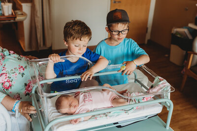newborn baby sister with older brothers in hospital