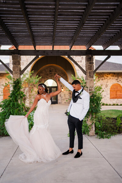 Bride is twirling her dress in front of a colorful wedding arch at the Schoolhouse Wedding Venue in Dallas Fort Worth. Taken by Danni Lea Photography, DFW Wedding Photographer