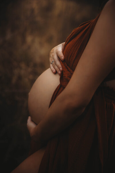 Expecting mother cradling her belly during a golden hour maternity session in The Woodlands, Texas