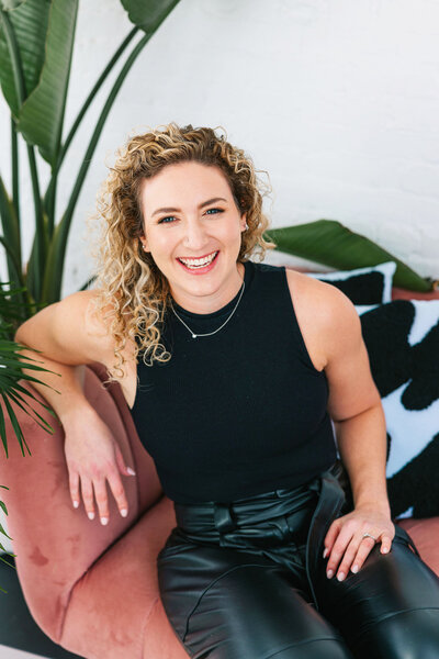 Rebecca sitting on pink chair, smiling at camera