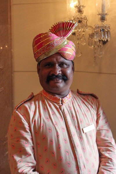 Hotel staff in a traditional Rajasthani uniform with an ornate pink and gold turban at a luxury palace hotel in Udaipur ©Stephanie Dosch | theViatrix India Private Luxury Travel