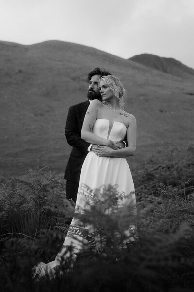 A couple hold each other in the mountains on their wedding day in Glencoe, Scotland