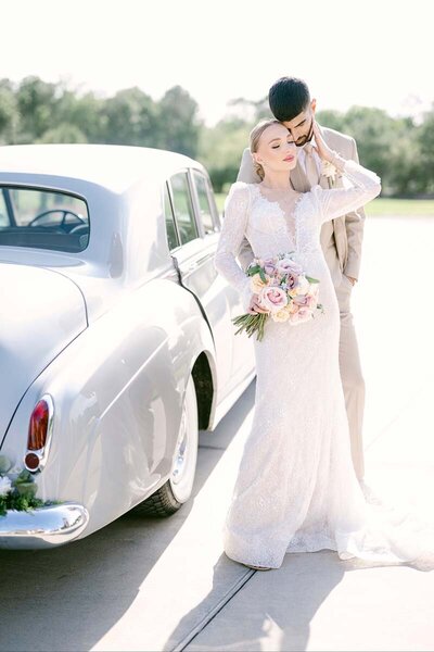wedding portrait of couple embracing each other near old sports car